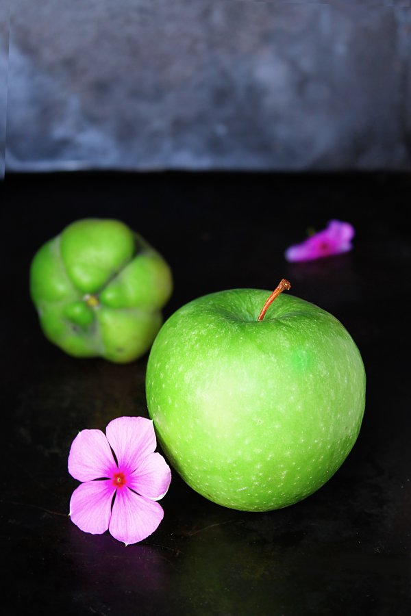 A green apple and a pink flower.