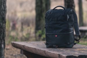 A black backpack outdoors on a wooden table.